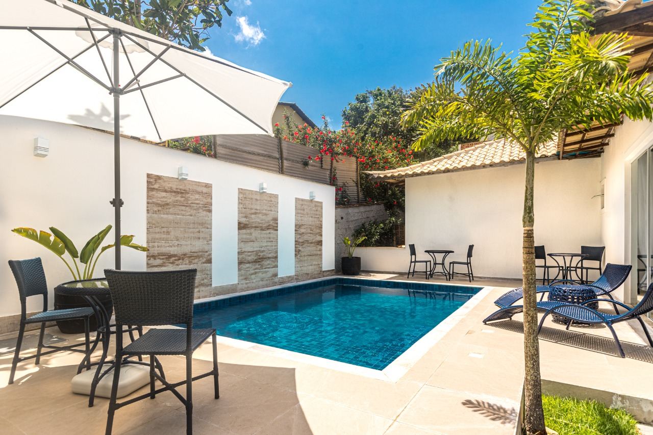 Área da piscina com ombrelone e coqueiro